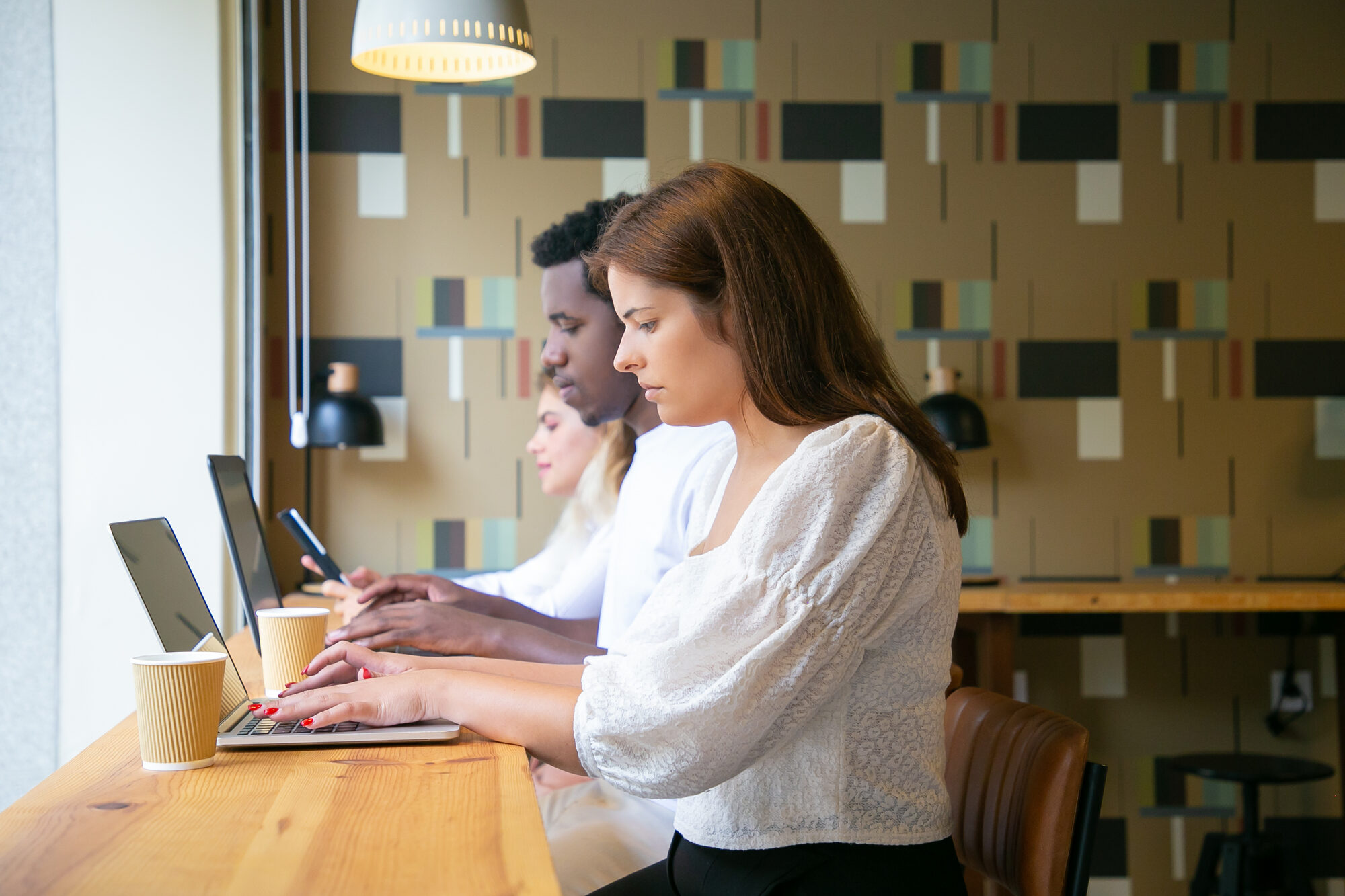 People working together at a table beside a window